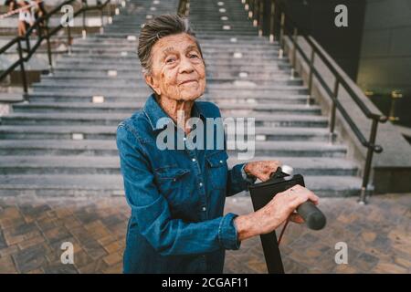 Une vieille femme près du scooter. Grand-mère femme progressiste. Senior s'amuser. La vieille femme apprécie ses passe-temps. Femme à la retraite utilisant un transport moderne et propre Banque D'Images