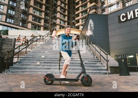 Une vieille femme près du scooter. Grand-mère femme progressiste. Senior s'amuser. La vieille femme apprécie ses passe-temps. Femme à la retraite utilisant un transport moderne et propre Banque D'Images