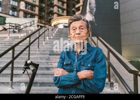 Une vieille femme près du scooter. Grand-mère femme progressiste. Senior s'amuser. La vieille femme apprécie ses passe-temps. Femme à la retraite utilisant un transport moderne et propre Banque D'Images