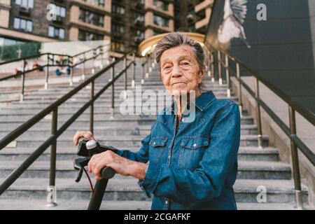 Une vieille femme près du scooter. Grand-mère femme progressiste. Senior s'amuser. La vieille femme apprécie ses passe-temps. Femme à la retraite utilisant un transport moderne et propre Banque D'Images