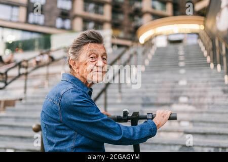 Une vieille femme près du scooter. Grand-mère femme progressiste. Senior s'amuser. La vieille femme apprécie ses passe-temps. Femme à la retraite utilisant un transport moderne et propre Banque D'Images