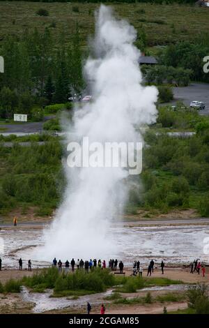 Strokkur lors d'une éruption de l'espace panoramique de Geysir. Les touristes se rassemblent autour pour observer l'éruption du Geyser. Cercle d'or, Islande. Banque D'Images