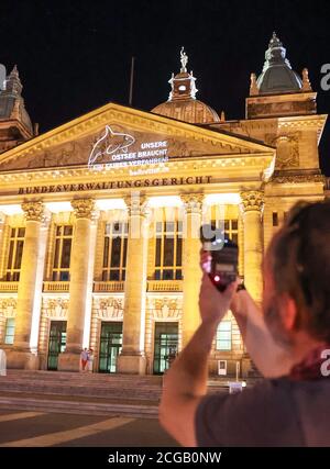 09 septembre 2020, Saxe, Leipzig: Un activiste du mouvement collectif Beltretter projette le slogan "notre mer Baltique a besoin d'un procès équitable" sur la façade de la Cour administrative fédérale. À peine deux semaines avant le début de l'audience sur le tunnel de la ceinture de Fehmarn, les opposants au projet majeur ont projeté une installation légère sur le tribunal administratif fédéral de Leipzig. À partir du 22 septembre, le tribunal entendra les plaintes de deux associations environnementales et de plusieurs compagnies de ferry contre les plans du tunnel. La structure de 18 kilomètres doit relier Fehmarn à l'isl danois Banque D'Images