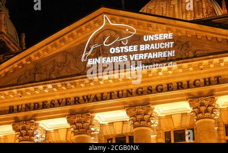 09 septembre 2020, Saxe, Leipzig: Un activiste du mouvement collectif Beltretter projette le slogan "notre mer Baltique a besoin d'un procès équitable" sur la façade de la Cour administrative fédérale. À peine deux semaines avant le début du procès du tunnel de la ceinture de Fehmarn, les opposants au projet majeur ont projeté une installation légère sur le tribunal administratif fédéral de Leipzig. À partir du 22 septembre, le tribunal entendra les plaintes de deux associations environnementales et de plusieurs compagnies de ferry contre les plans du tunnel. La structure de 18 kilomètres relie Fehmarn à l'islan danois Banque D'Images