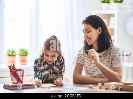 Bonne famille. Mère et fille apprennent à écrire. La femme adulte enseigne l'alphabet à l'enfant. Banque D'Images