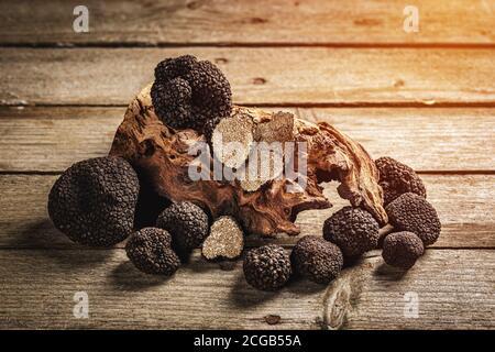 Champignons entiers et tranches de truffe noire sur fond de bois Banque D'Images