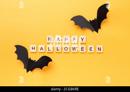 Joyeux Halloween blocs de bois et chauves-souris en papier noir sur fond jaune. Concept Halloween. Flat Lay, vue de dessus - image Banque D'Images