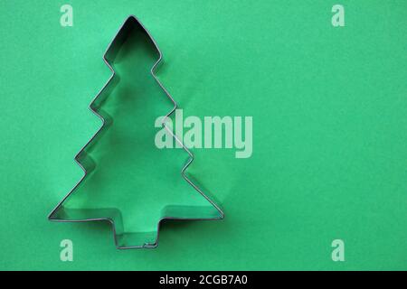 Emporte-pièce en acier en forme d'arbre de Noël sur fond vert avec espace pour les copies. Banque D'Images
