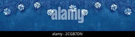 Fond de Noël avec branches d'arbre et cônes sur fond de pierre noire. Longue bannière horizontale. Couleur de l'année 2020 bleu classique - image Banque D'Images