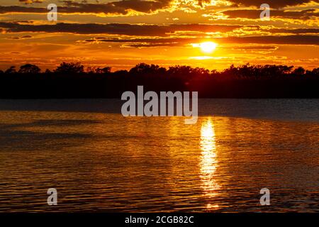 Coucher de soleil sur Eastern Neck Island réserve naturelle sur la rive est de la baie de Chesapeake, Maryland. La lumière du soleil se reflète dans les nuages et l'eau calme Banque D'Images