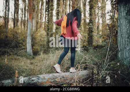 Femme marchant sur un tronc à travers la forêt pendant le jour Banque D'Images