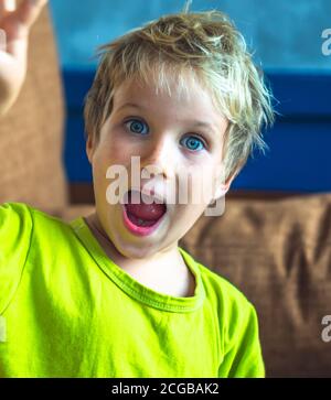 Portrait espiègle mignon blond bleu eyed garçon faisant des taches de rousseur visage jouer en riant dans l'humeur heureuse. Photo amusante, style de vie de bonheur. Garderie, joies simples Banque D'Images