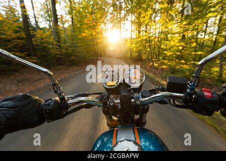 Vue du conducteur de moto de la perspective de la conduite dans le paysage de Foreste pendant lever du soleil Banque D'Images