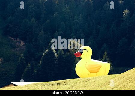 Canard en caoutchouc jaune géant dans la colline verte entourée par la forêt de montagnes. Entrée de la piscine Banque D'Images