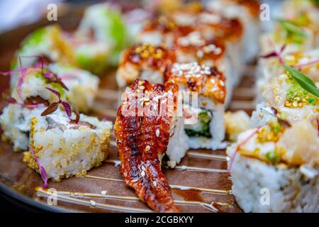 Différents petits pains japonais et sushis sur une assiette. Rouler avec de l'anguille. Banque D'Images