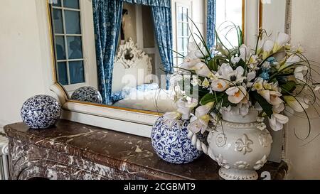 Un vase antique avec un bouquet de roses supports sur la cheminée dans la chambre et se reflète dans le miroir Banque D'Images