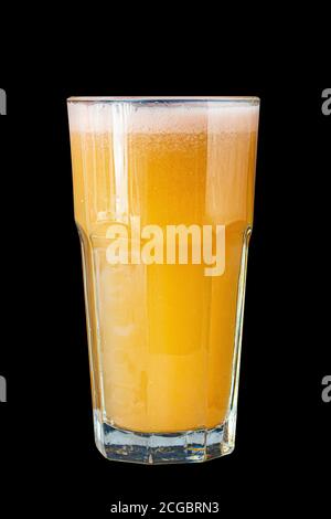 Smoothie aux agrumes d'orange dans un grand verre contre un mur en pierre sombre Banque D'Images