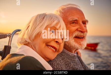 Amoureux. Portrait rapproché d'un beau et heureux couple senior qui se tient, se détendant et souriant tout en naviguant ensemble dans la mer au coucher du soleil Banque D'Images