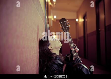 Jeune femme chanteuse avec portrait de guitare dans un couloir intérieur Banque D'Images