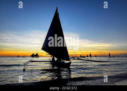 Vue panoramique des voiliers silhouette pour les touristes le long de la plage blanche et à l'horizon au coucher du soleil sur l'île Boracay, Philippines, Asie Banque D'Images