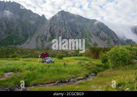 Camping hors-bord sur l'île de Vega classée au patrimoine mondial de l'UNESCO à Helgeland, Norvège du Nord avec tente sur toit sur voiture 4x4 avec montagnes en arrière-plan Banque D'Images