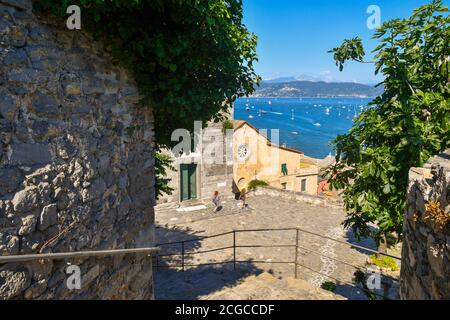 Vue panoramique sur le golfe des poètes avec le parvis de l'église Saint-Laurent et deux touristes en été, Porto Venere, la Spezia, Ligurie, Italie Banque D'Images