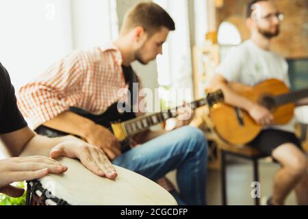 Chansons. Le groupe de musiciens s'est rassemblé sur le lieu de travail de l'art avec des instruments. Hommes et femmes caucasiens, musiciens, jouant et chantant ensemble. Concept de musique, passe-temps, émotions, métier artistique. Banque D'Images