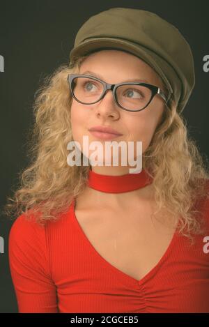 Jeune belle femme aux cheveux blonds courbés sur fond gris Banque D'Images