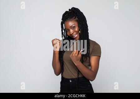 Excitée jeune afro-américaine heureuse se sentant surjoyeuse isolée sur fond gris studio. La chance euphorique fille noire gagnante célébrant la victoire vict Banque D'Images