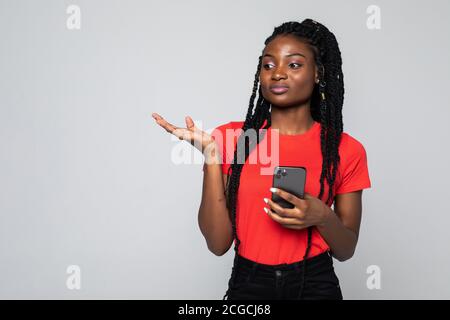 Une jeune fille millénaire africaine folle isolée sur fond gris se sent furieux d'avoir des problèmes de smartphone, la jeune femme biraciale en colère devient irritante Banque D'Images