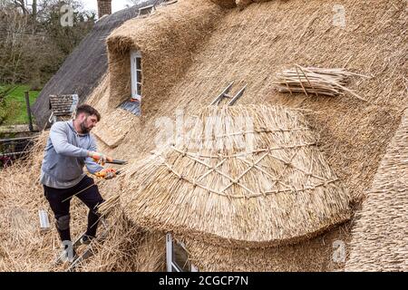 des ouvriers qui patchent le toit d'un vieux cottage Banque D'Images