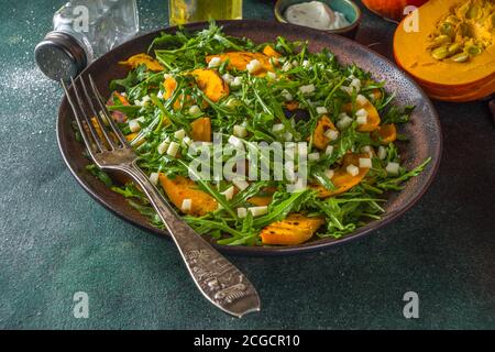 Salade de potiron maison avec tranches de potiron grillées, arugula et fromage. Recette de salade de citrouille d'automne, arrière-plan sombre Banque D'Images
