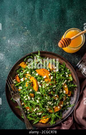 Salade de potiron maison avec tranches de potiron grillées, arugula et fromage. Recette de salade de citrouille d'automne, arrière-plan sombre Banque D'Images