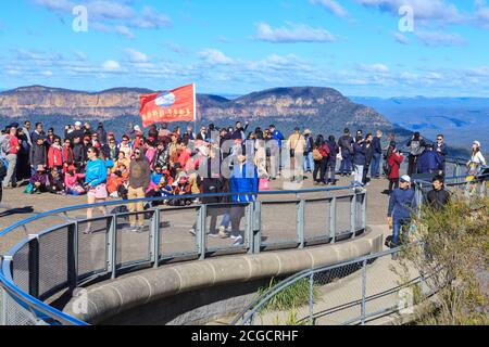 Les touristes, y compris un groupe chinois avec un drapeau, au point d'observation d'Echo point dans les Blue Mountains, en Australie Banque D'Images