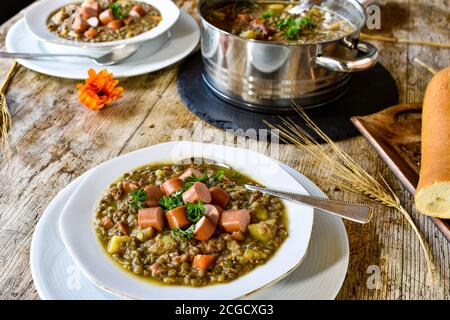 ragoût de lentilles copieux avec saucisses telles que hot dogs on une assiette à soupe blanche servie chaude sur une table Banque D'Images