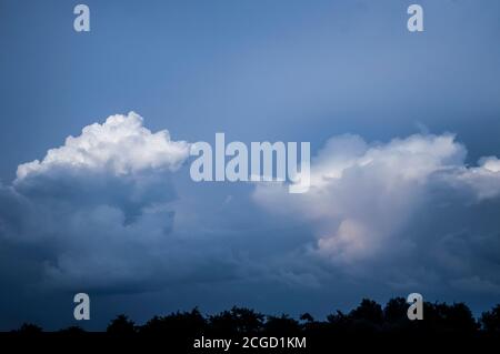 Nuages au coucher du soleil quand il est presque sombre. Nuages blancs sur un ciel sombre dans la soirée Banque D'Images