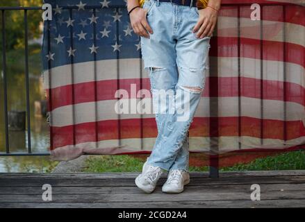 jambes dans un jean déchiré sur un fond de tissu avec Un imprimé du drapeau américain Banque D'Images