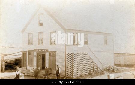 Photo antique c1890 des propriétaires, des employés et de la famille de H.D. Magasin marron à l'extérieur de leur bâtiment. En fonction des articles à l'extérieur, il s'agit d'un magasin de quincaillerie ou d'articles généraux. Emplacement exact inconnu, mais près de Boston, Massachusetts, États-Unis. SOURCE : PHOTO ORIGINALE Banque D'Images