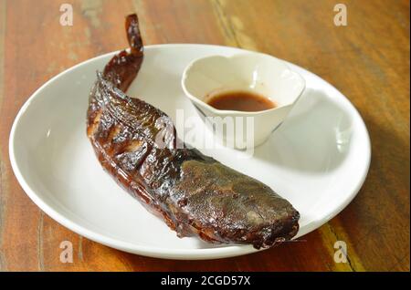 poisson-chat grillé en trempant avec une tasse de sauce épicée sur le plat Banque D'Images