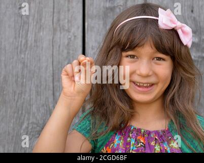 Mignon mixte-race petite fille (est asiatique / caucasien) montre avec sa main droite le signe de la main chinoise pour le numéro 7 (photo série: Image no. 7 de 10). Banque D'Images