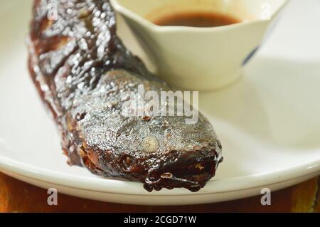 poisson-chat grillé en trempant avec une tasse de sauce épicée sur le plat Banque D'Images