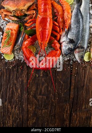 Homard entier avec fruits de mer, crabe, moules, crevettes, poisson et autres coquillages servis sur glace pilée et table en bois Banque D'Images