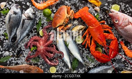 Homard entier avec fruits de mer, crabe, moules, crevettes, poisson, steak de saumon, pieuvre, huîtres et autres coquilles servis sur glace pilée. Banque D'Images