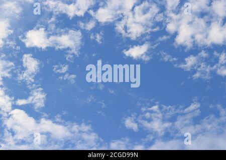 Image d'un ciel avec de petits nuages blancs dispersés dans le ciel et un espace vide au milieu de l'image pour placer du texte. Banque D'Images