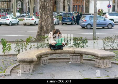 MADRID, ESPAGNE - 19 FÉVRIER 2020 : une jeune fille est assise sur un banc de pierre dans la ville de Madrid. Banque D'Images