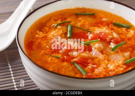Soupe facile aux œufs de tomates ou soupe aux fleurs d'œuf dans un bol sur la table. Horizontale Banque D'Images