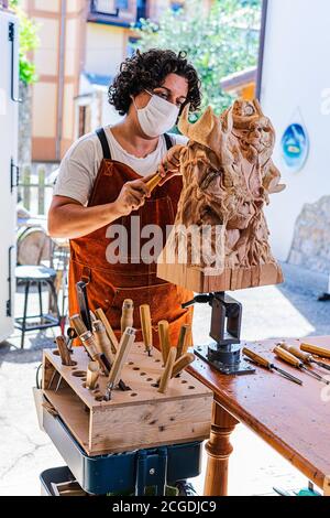 Sculpter avec masque sculptant figure en bois Banque D'Images