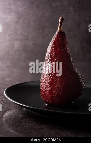 Poires pochées au vin rouge sur fond noir Banque D'Images