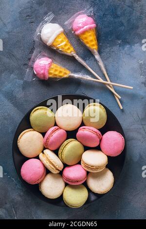 Des sucettes et une plaque complète de macarons sur la table, vue du dessus Banque D'Images