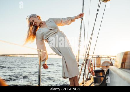 Belle femme âgée avec de longs cheveux posant sur le yacht et vue sur l'eau Banque D'Images